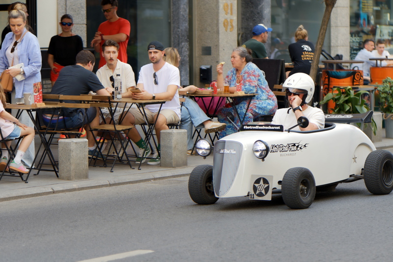 6 - A white Wenckstern Mini Hot Rod touring vehicle with a Hot Rod Fun Bucharest logo cruising on a city street